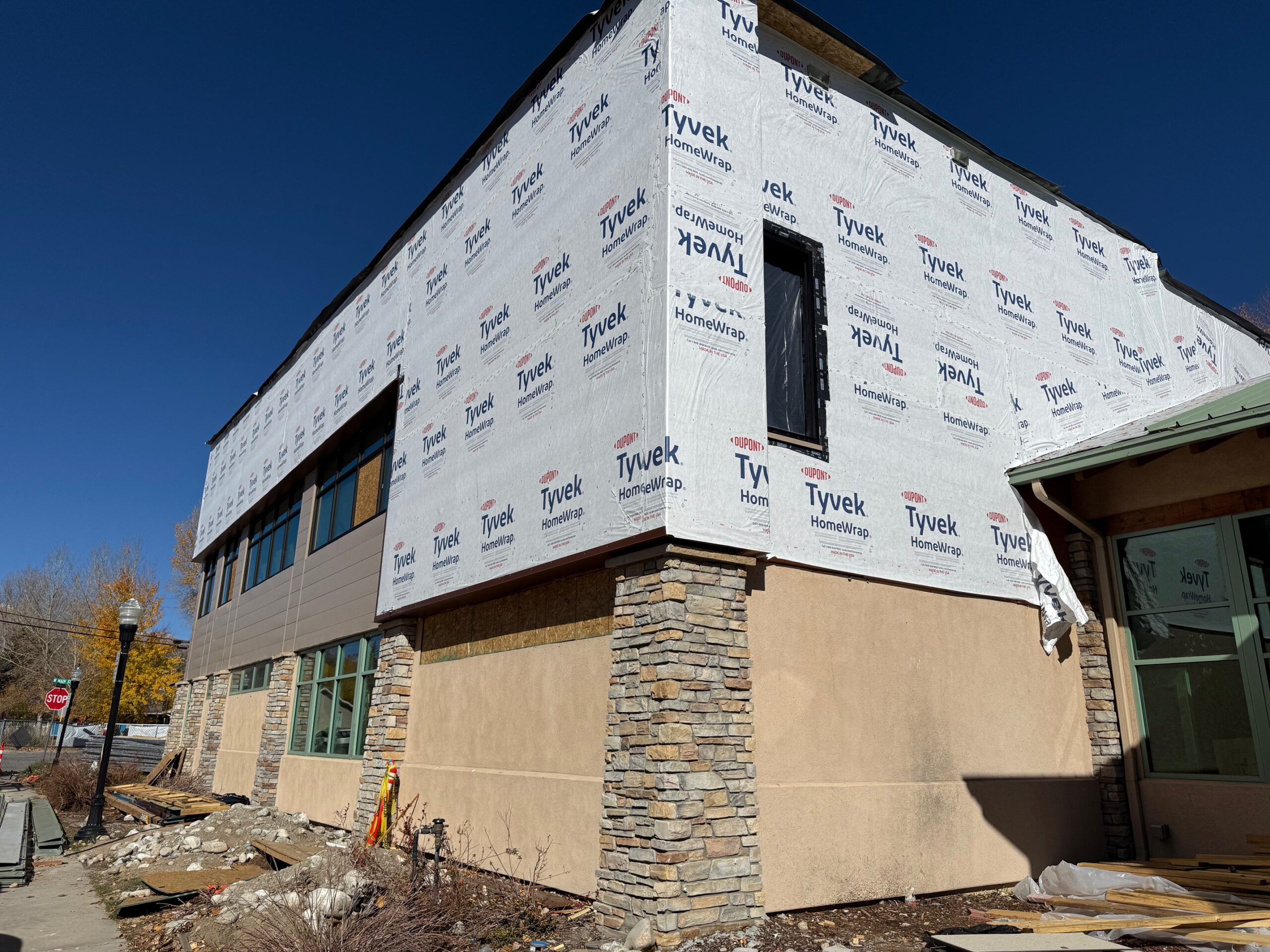 Exterior of building with siding install begun and window install in progress.